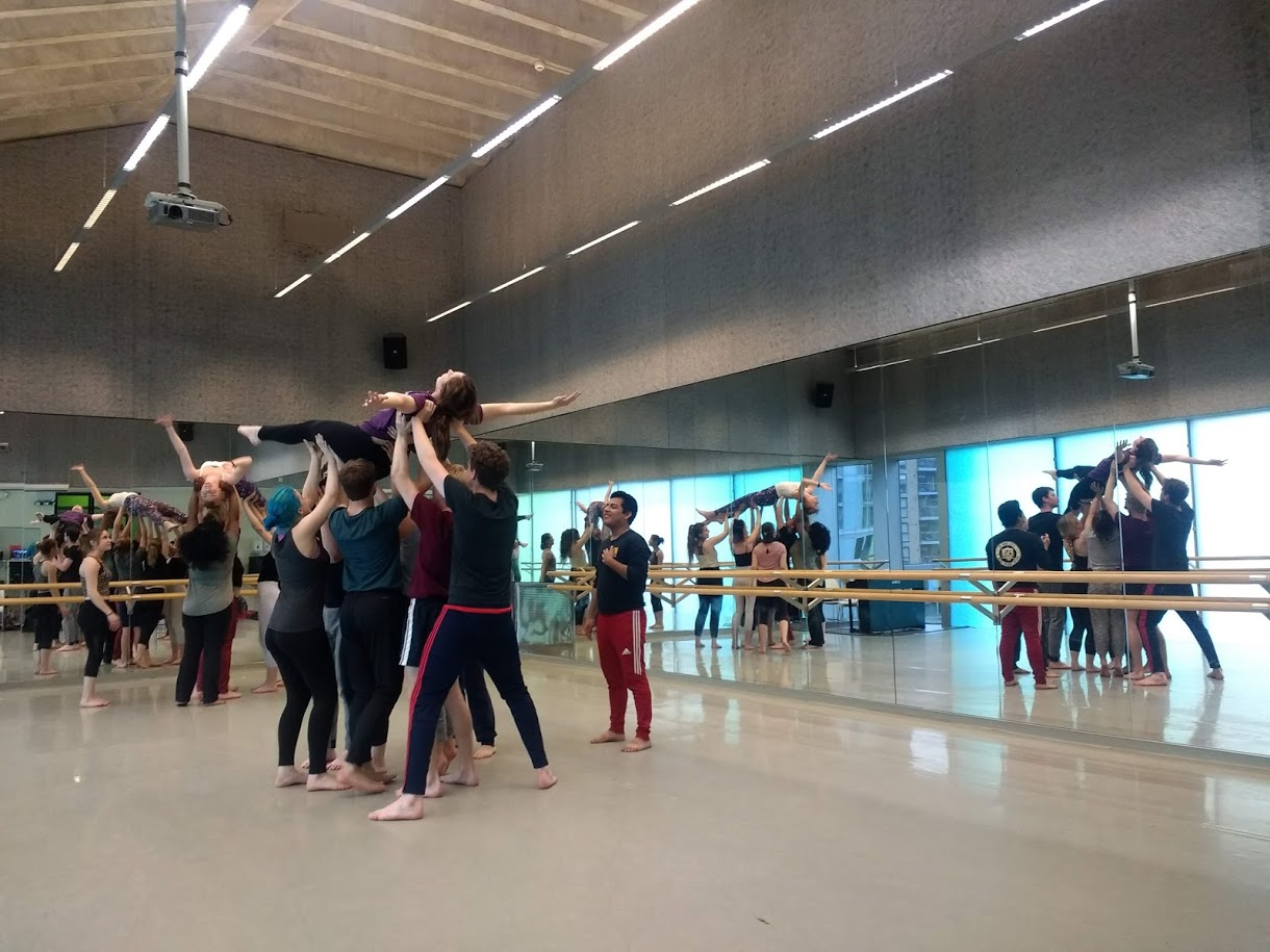 Students dancing in studio, lifting one student in the air.
